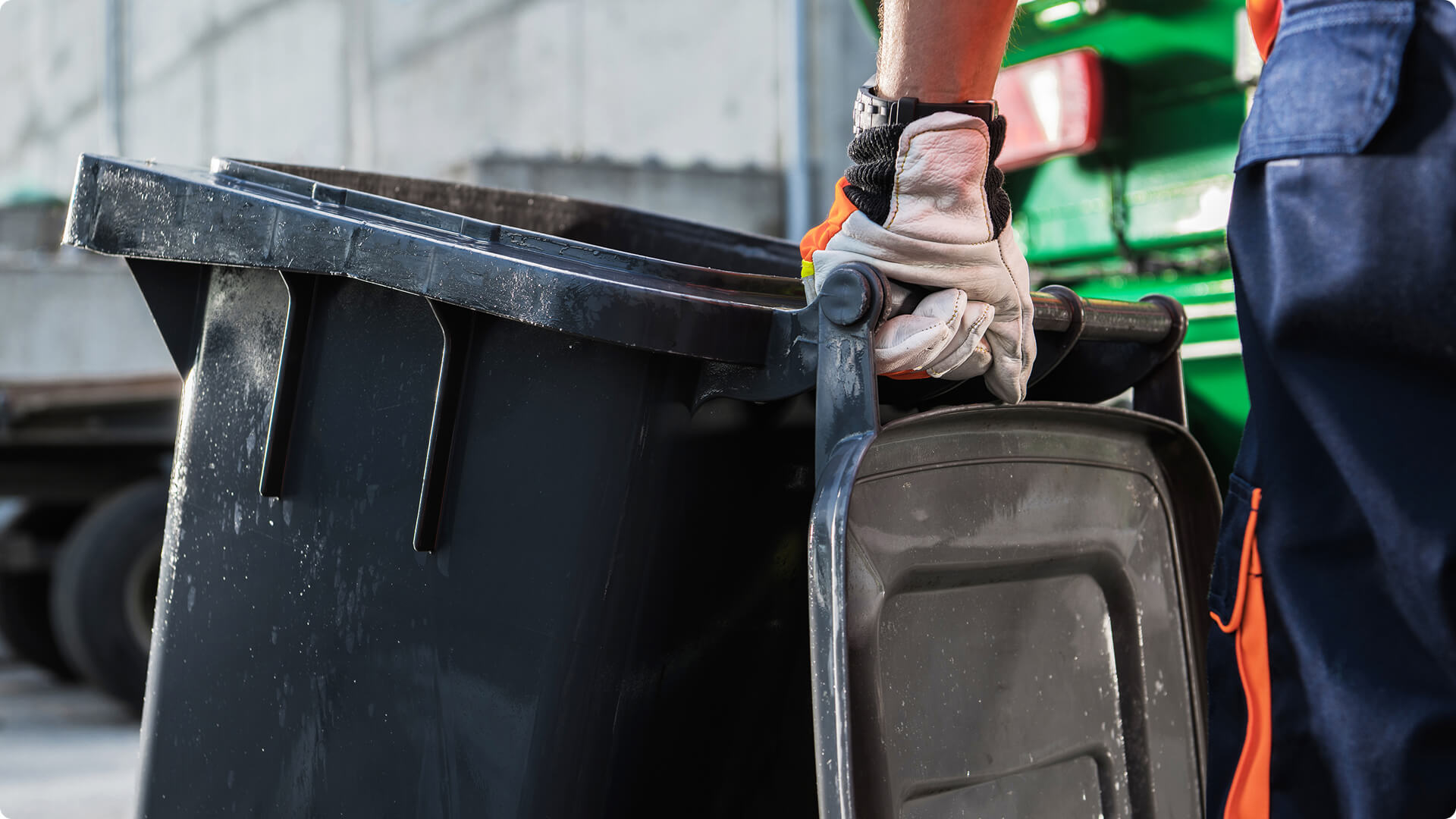Worker handling a large commercial wheelie bin during waste collection